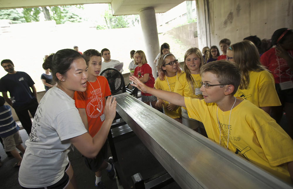 Monica Meng '18 encourages a boy wearing a yellow shirt in Lafayette's STEAM summer camp.