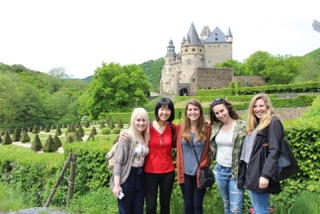 Danhui Zhang '18 and some fellow study abroad students pose for a photo in Germany with a castle in the background