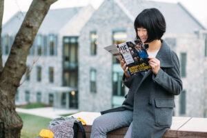Danhui Zhang '18 reads a German magazine with the Oechsle Center for Global Perspectives in the background