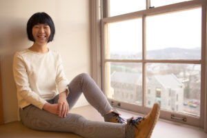 Danhui Zhang '18 sits by a window and smiles.