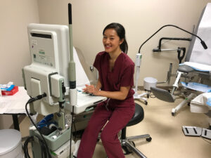 Jackie Kikuchi sits and smiles in the exam room of her medical facility