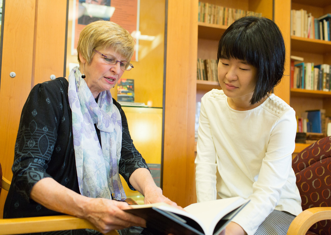 German Professor Marguerite Lamb-Faffelberger and Danhui Zhang '18 hold and discuss a book.