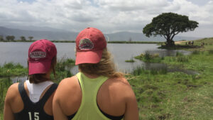 Two women students look at a lake and surrounding land in Tanzania.