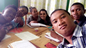Malagasy students pose for a photo at a table.